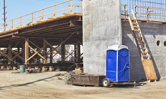 a row of modern portable restrooms at a busy construction site, designed for easy use and maintenance